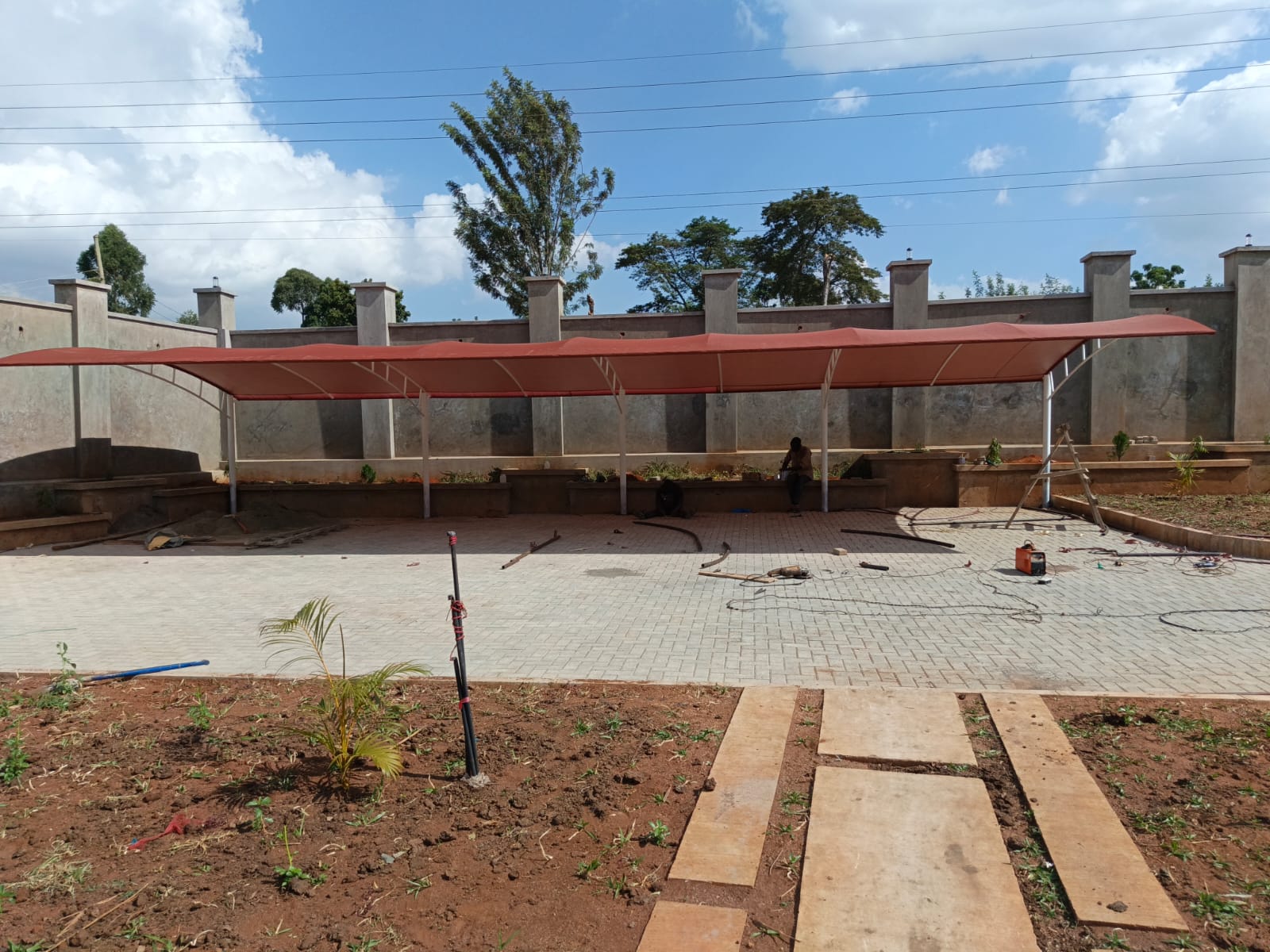 Long red cantilever parking shade along a boundary wall